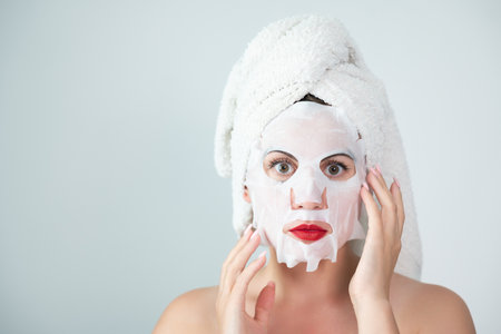 Portrait of a woman with a cotton mask to moisturize her face, place for advertising and inscription.の写真素材