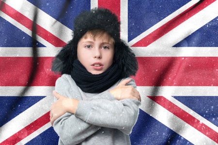 The cold winter and the consequences of gas sanctions, the consequences of the war in Ukraine, the shortage of gas and heat in the United Kingdom, a European schoolboy boy is freezing in the winter heating period.の写真素材