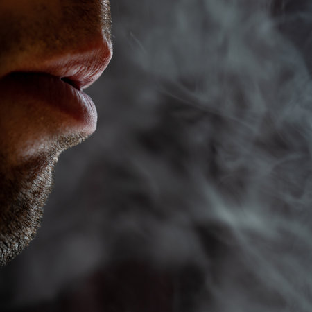 Male lips blowing smoke close-up, cigarette smoke and lips on black background, male unshaven and short beard.の写真素材