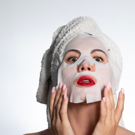 Woman with a towel on her hair and a mask on her face, skin and hair care, place for advertising and inscription.の写真素材