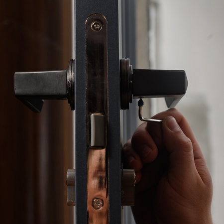 The craftsman installs the door handle with the help of a sprocket key, installation work with doors, installation close-up.の写真素材