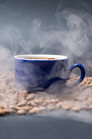 Cup of coffee and coffee beans on a black background, aromatic and energy drink, light steam from coffee.の写真素材