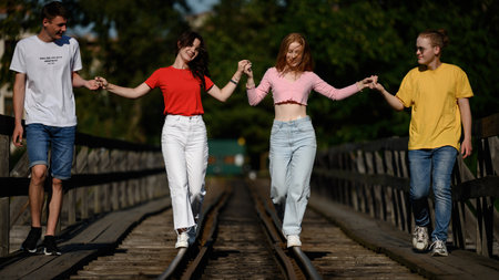 Ivano-Frankivsk, Ukraine July 14, 2022: A group of teenagers take pictures on a railway bridge over a river, a school photo session.のeditorial素材