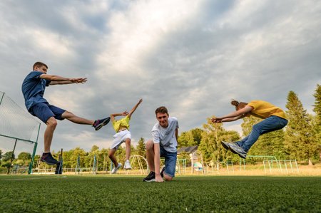 Ivano-Frankivsk, Ukraine, July 14, 2022: School-age teenagers pose for a photo on the sports ground, hand slamming on the ground.のeditorial素材