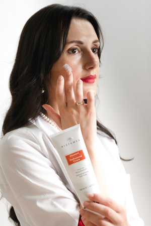 Ivano-Frankivsk, Ukraine, July 27, 2022: a cosmetologist applies cream to the face of the Histomer company. a portrait of a cosmetologist on a white background.のeditorial素材