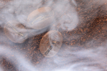top view of coffee beans and ground coffee steaming with heat, roasted coffee, smoky coffee texture.