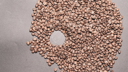 Evenly scattered coffee beans on a black background, roasted brown aromatic coffee beans.の写真素材