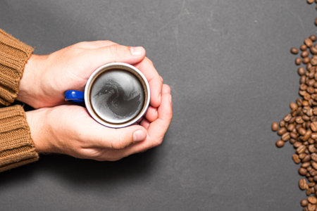 Male hands holding coffee on a dark background, a cup of black coffee in hands.の写真素材