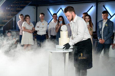 Ivano-Frankivsk, Ukraine June 26, 2021: A waiter brings out a cake for the bride and groom, a festive event.のeditorial素材