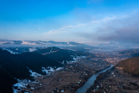 Viaduct railway bridge in the Carpathians of Ukraine, a view of the bridge from a height, a winter panorama of a village in the mountains.の写真素材