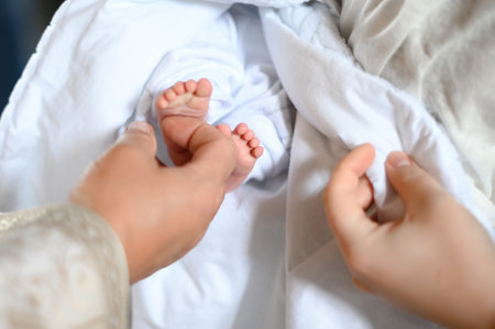 The sacrament of baptism of a baby in the church, the baby's legs on a white sheet.