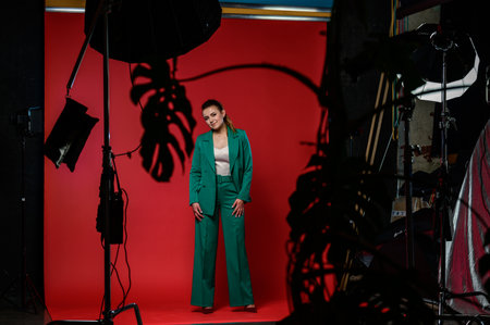Ivano-Frankivsk, Ukraine January 30, 2022: full-length portrait of a girl in a studio, photo on a red background, girl in a green suit.のeditorial素材