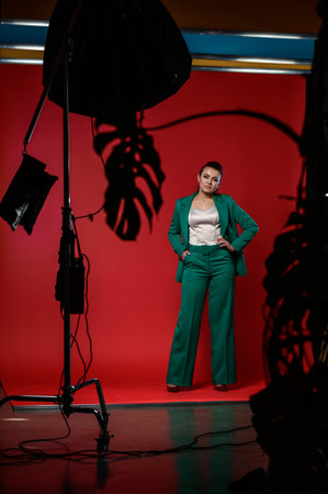 Ivano-Frankivsk, Ukraine January 30, 2022: full-length portrait of a girl in a studio, photo on a red background, girl in a green suit.のeditorial素材
