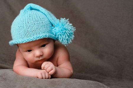 Rivne, Ukraine April 25, 2022: a newborn baby boy in a blue cap lies on his stomach, close-up portrait.のeditorial素材