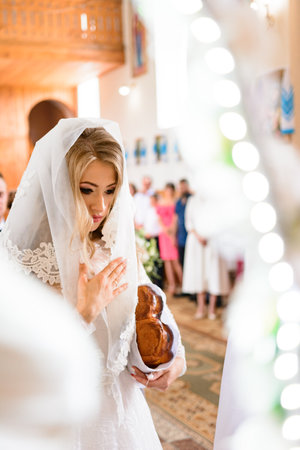 Ivano-Frankivsk, Ukraine August 1, 2021:The bride prays in the church after the sacrament of the wedding, the bride is dressed in a veil on her head.のeditorial素材