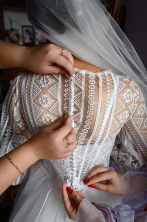 The bride's back, dressed in a wedding dress, girls help the brides to wear a dress.