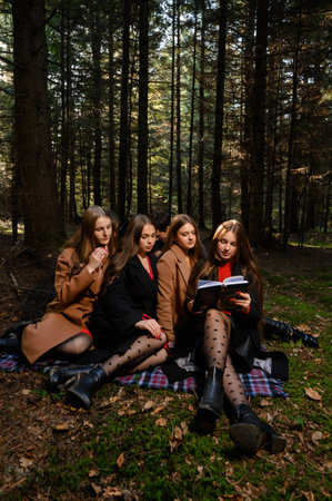 Ivano-Frankivsk, Ukraine October 14, 2022: teenage schoolchildren reading a book in the forest, a group of children in the park, a group of classmates in the autumn forest.のeditorial素材