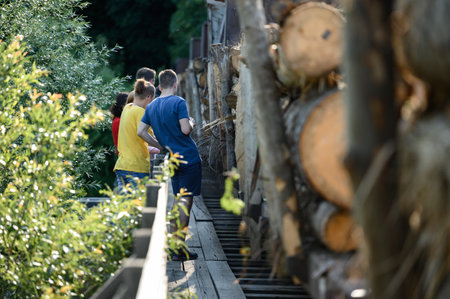 careless children on a railway bridge, through which wagons with wood pass, children hold on to the bridge's rafters.の写真素材