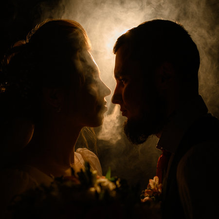 Ivano-Frankivsk, Ukraine July 31, 2022: A loving couple looks into each other's eyes, silhouettes of people in smoke on a black illuminated background, a romantic evening for the lovers.のeditorial素材