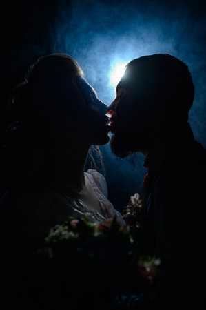 Ivano-Frankivsk, Ukraine July 31, 2022: A loving couple looks into each other's eyes, silhouettes of people in smoke on a black illuminated background, a romantic evening for the lovers.のeditorial素材