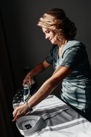 Ivano-Frankivsk, Ukraine October 2, 2022: Ukrainian traditions at a wedding, mother ironing the groom's shirt, groom's morning.のeditorial素材