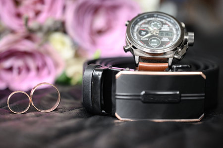 Belt with a watch, wedding rings and a bouquet of flowers, composition of the morning of the groom,...