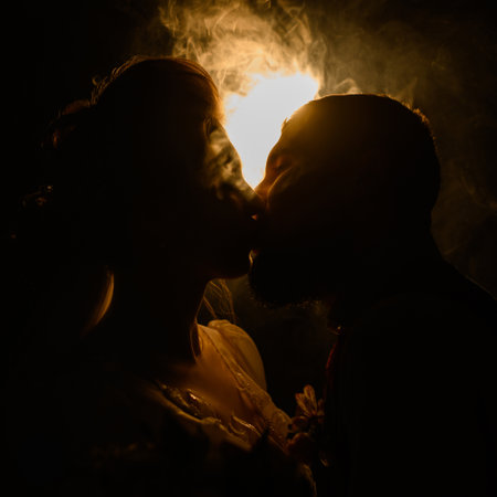 Ivano-Frankivsk, Ukraine July 31, 2022: A loving couple looks into each other's eyes, silhouettes of people in smoke on a black illuminated background, a romantic evening for the lovers.のeditorial素材