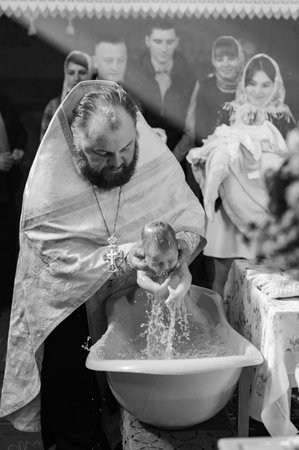 Transcarpathia, Ukraine October 16, 2022: Moments of baptism of the child in the temple of God, Christian traditions, moments of immersion in the water.のeditorial素材