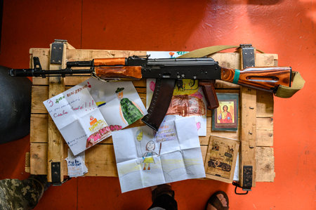 Kyiv, Ukraine July 1, 2022: children's drawings and machine gun, helmet and military ammunition,...