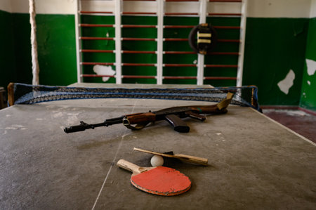 An abandoned sports hall at the school, sports equipment destroyed by time, automatic rifle in the gym in an abandoned school.の写真素材