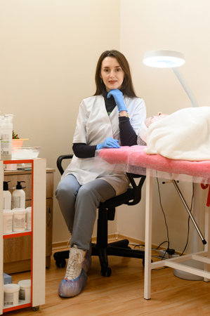 Ivano-Frankivsk, Ukraine December 20, 2022: Portrait of the beautician in the office during the reception of the client, the client with a mask on her face.の写真素材
