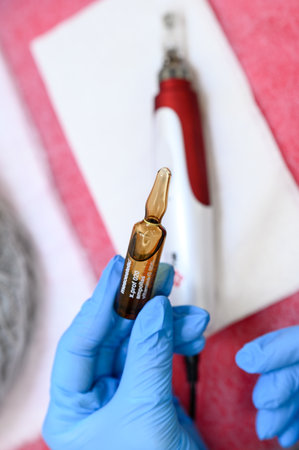 Ivano-Frankivsk, Ukraine December 20, 2022: Ampoule with vitamin C for application directly to the face for the procedure of mesotherapy with the help of dermapen, application of liquid to the face.のeditorial素材