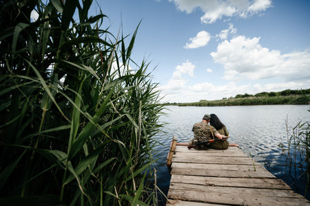 A couple in love, where a military man is sitting on a bridge near a pond, a meeting of a husband and wife during the war.の写真素材