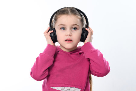 A child with headphones on a white background, a cheerful and beautiful girl with headphones, copy space on a white background.の写真素材