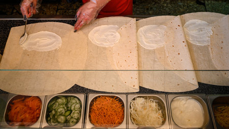 Several sheets of pita bread on the work surface and a bowl with already prepared and chopped...