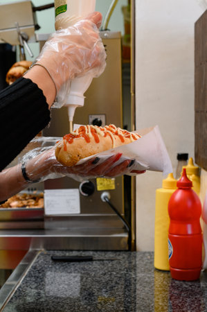 The process of making a hot dog, a worker fulfills a customer's order and prepares a hot dog, a fast food restaurant.の写真素材