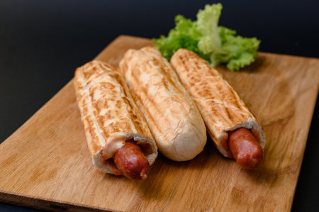 three french hot dogs on a wooden board on a black background, fast food and copy space.の写真素材