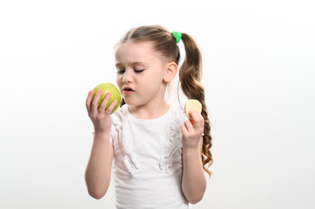 Green apple and potato chips, healthy and unhealthy food for children, little girl chooses apple over chips, child portrait on white background.の写真素材