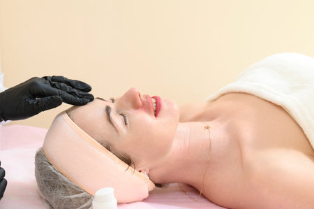 Facial massage in a spa salon, a cosmetologist performs a relaxing procedure on a girl's face, anti-aging massageの写真素材