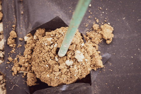 A man drills a hole with a hand drill through agrofibre, field and manual work, agrofibre from...