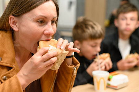 Ivano-Frankivsk, Ukraine June 7, 2023: A young girl eats a burger at McDonalds.のeditorial素材