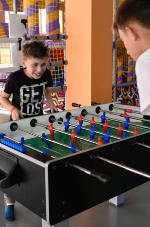 Two boys in the game room playing table football, mental and active recreation.