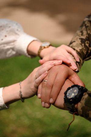 Hands of the bride and groom with rings on their fingers close-up, wedding day. Groom in military uniform.の写真素材