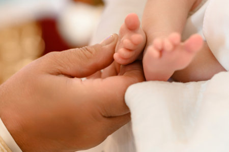 The priest performs the rite of baptism of the child and anoints the leg with holy myrrh, the sacrament of Christian baptism.の写真素材