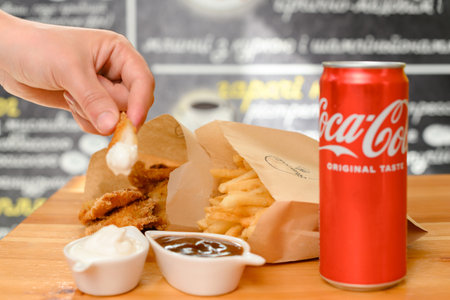 Ivano-Frankivsk, Ukraine March 26, 2023: Female hand dips chicken nuggets in sauceのeditorial素材