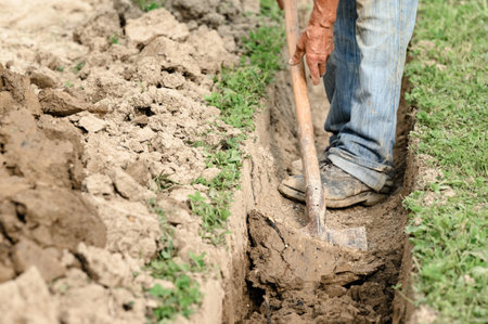 A man shovels a trench for drainage and sewage, close up.の写真素材