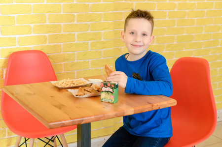 Ivano-Frankivsk, Ukraine March 26, 2023: little smiling boy eating chicken nuggets in a cafeのeditorial素材