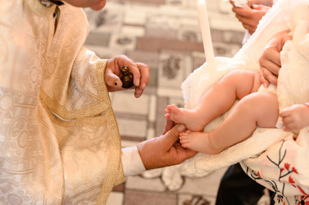 The priest performs the rite of baptism of the child and anoints the leg with holy myrrh, the sacrament of Christian baptism.の写真素材