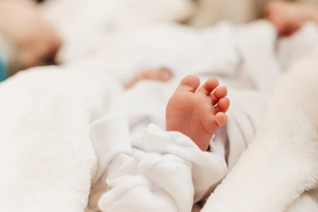 A baby's small leg during baptism on a white sheet, newborn baby.の写真素材