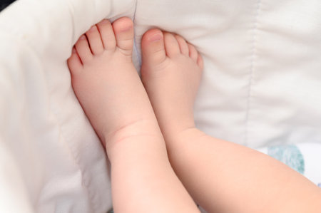 The baby's small legs rest against the side of the stroller, legs close-up.の写真素材